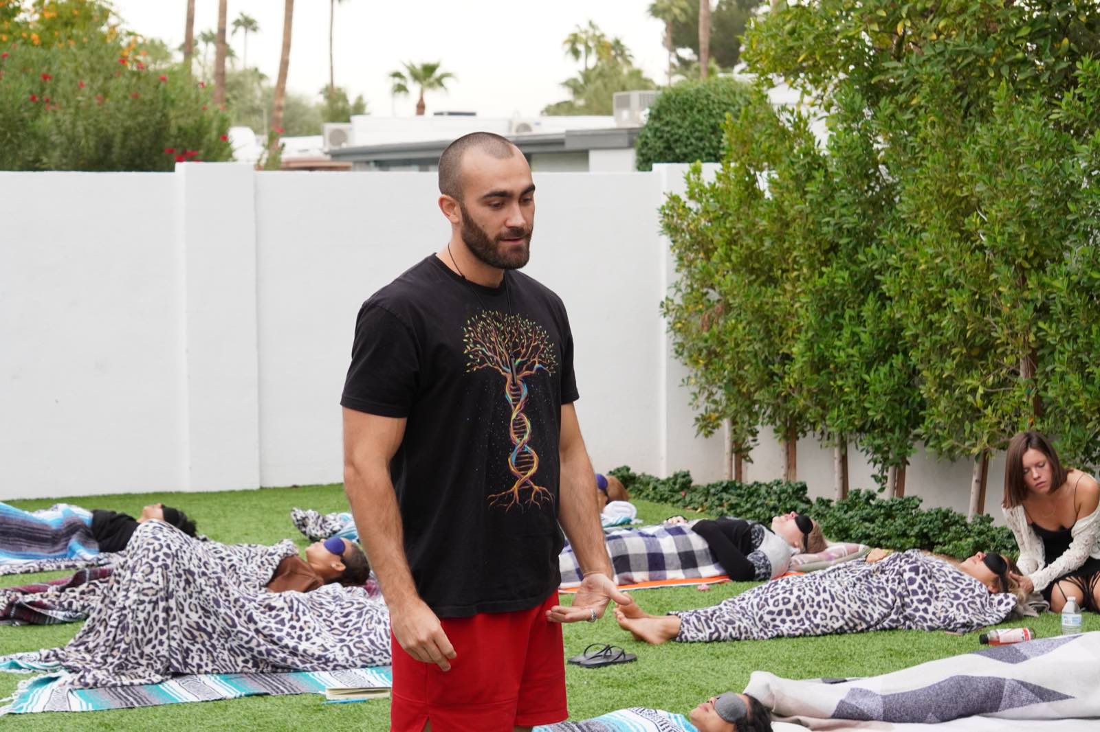 Ryan McBurney leading an outdoor Breathwork session, participants resting on mats
